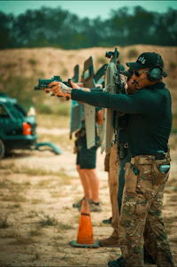 a man holding a gun in front of a car